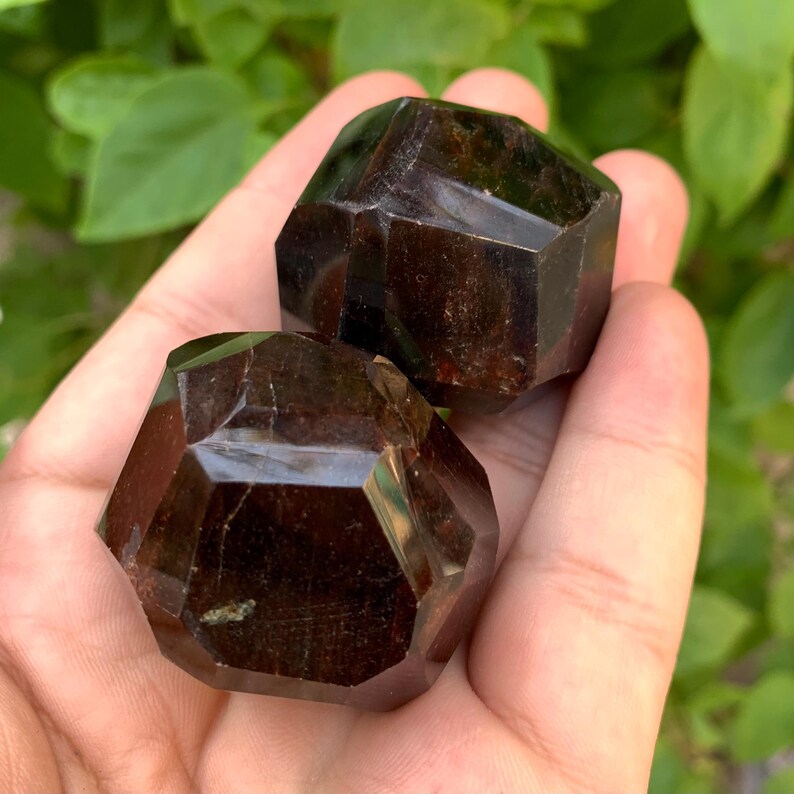 Puede incluir: Dos cristales de piedra preciosa de color rojo oscuro, facetados. Los cristales tienen forma de oct&oacute;gono y un acabado brillante.