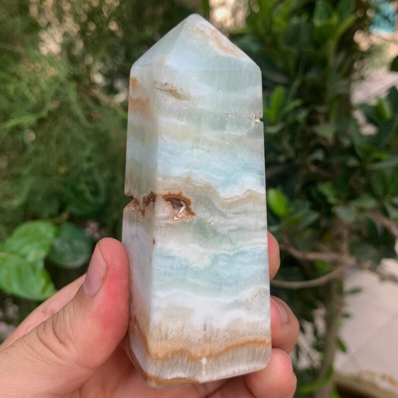 Puede incluir: Una torre de cristal azul claro y marr&oacute;n con una punta puntiaguda. El cristal es liso y pulido.