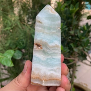 Puede incluir: Una punta de cristal de color azul claro, blanco y marr&oacute;n. El cristal est&aacute; pulido y tiene una punta puntiaguda.