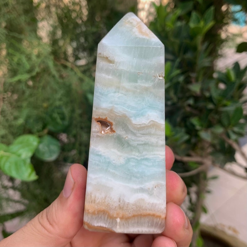 Puede incluir: Una punta de cristal de color azul claro, blanco y marr&oacute;n. El cristal est&aacute; pulido y tiene una punta puntiaguda.