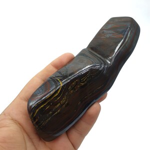 以下が含まれることがあります： 金色と赤色の線が渦巻く模様の、大きく滑らかな濃い灰色と茶色の石。この石は、自然で、生で、研磨されていないタイガーアイロンの塊です。