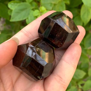 Puede incluir: Dos cristales de piedra preciosa facetados de color marr&oacute;n oscuro. Los cristales tienen forma de pir&aacute;mide con una base plana.