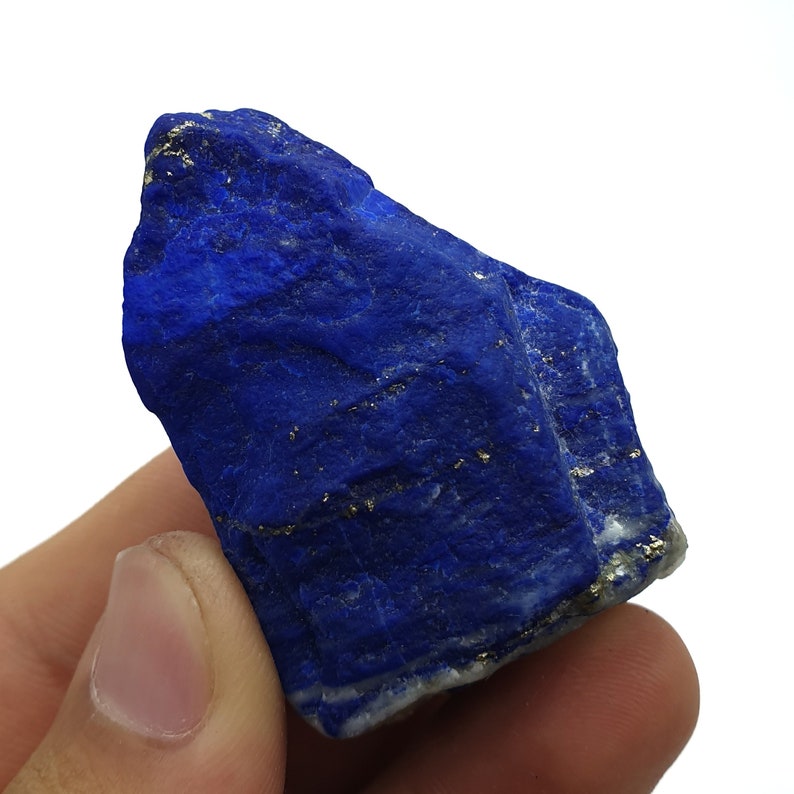 May include: A large, rough, blue lapis lazuli stone with gold pyrite inclusions. The stone is a deep, rich blue color and has a natural, unpolished surface.