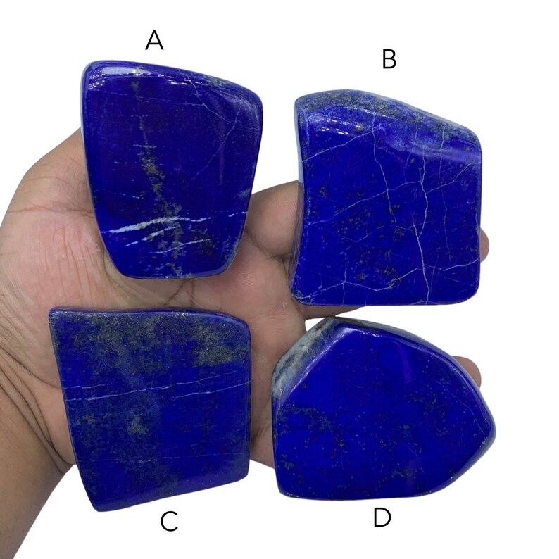 May include: Four pieces of raw, blue lapis lazuli stone. The stones are irregularly shaped and have a rough, natural texture. The stones are labeled A, B, C, and D.