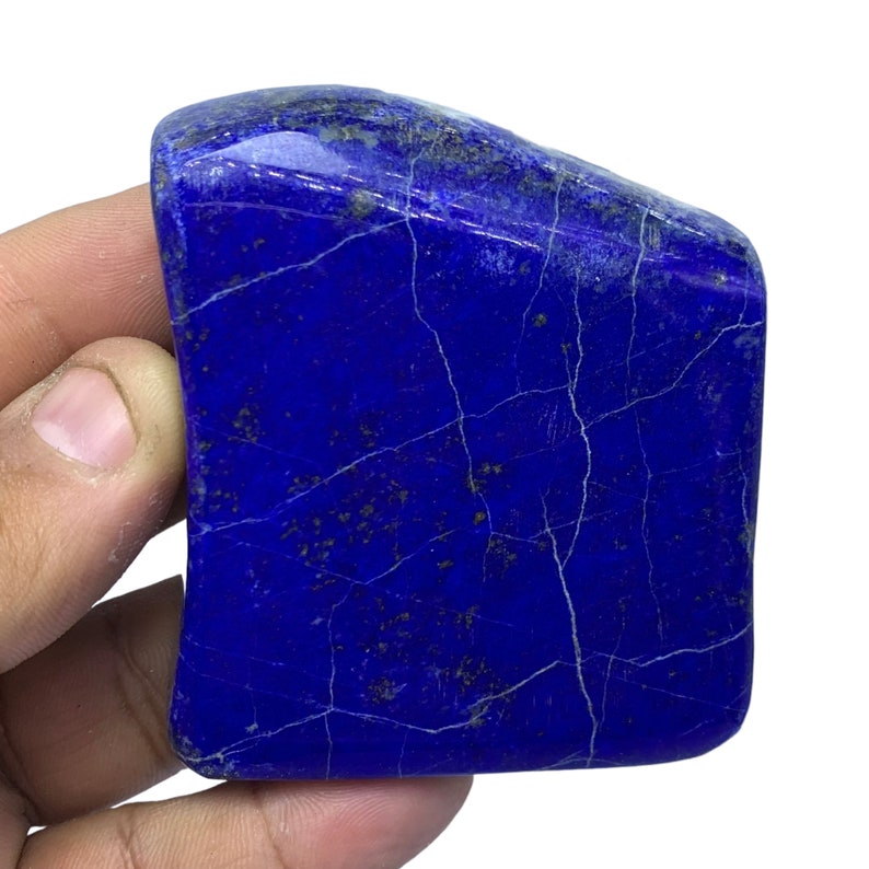 May include: A large, deep blue, irregularly shaped piece of lapis lazuli with white veins and gold flecks.