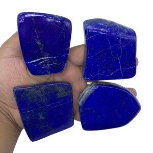 May include: Four rough-cut, dark blue Lapis Lazuli stones with white veins and gold flecks. The stones are arranged in a square shape.