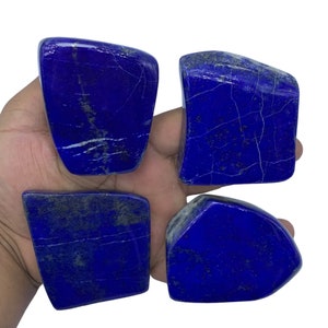 May include: Four smooth, irregularly shaped pieces of Lapis Lazuli, a deep blue gemstone with white veins and flecks of gold pyrite. The stones are arranged in a square shape.