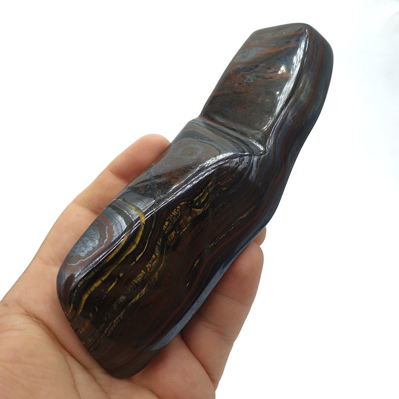 以下が含まれることがあります： 滑らかで磨かれた表面を持つ、大きく、濃い茶色、黒、金色のタイガーアイストーン。石には独特の層状のパターンがあります。