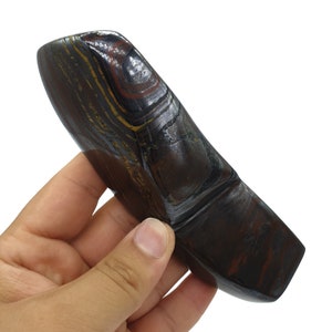 以下が含まれることがあります： 独特な湾曲した形をした、滑らかな濃い茶色と金のタイガーアイストーン。石は、茶色、金色、黒色の色合いの層状の縞模様をしています。