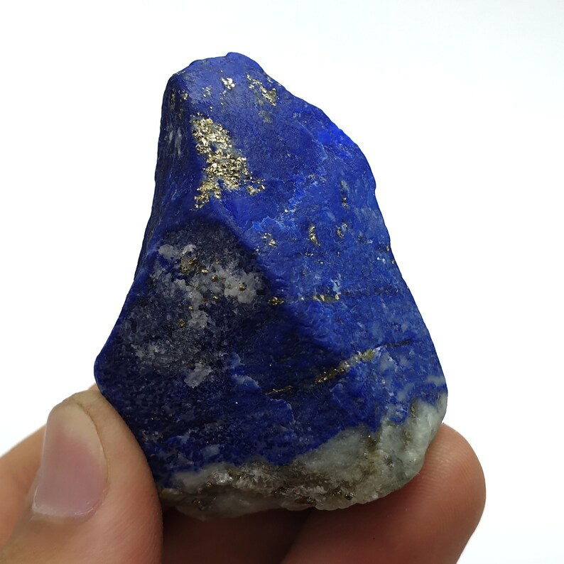 May include: A large, rough, blue lapis lazuli stone with gold pyrite inclusions. The stone has a natural, irregular shape.