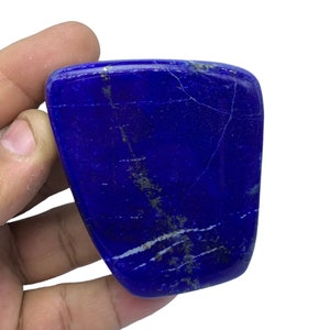 May include: A smooth, polished, dark blue lapis lazuli stone with white and gold veins. The stone is irregularly shaped and has a slightly rounded edge.