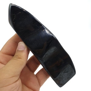 以下が含まれることがあります： 長く薄い刃の形をした黒と虹色の黒曜石の結晶。結晶は滑らかで磨かれた表面とわずかに湾曲した形をしています。