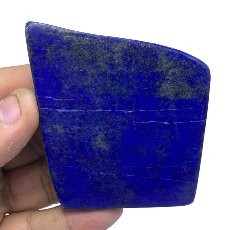 May include: A large, deep blue lapis lazuli slab with white veins and flecks of gold pyrite. The slab has a rough, natural surface.