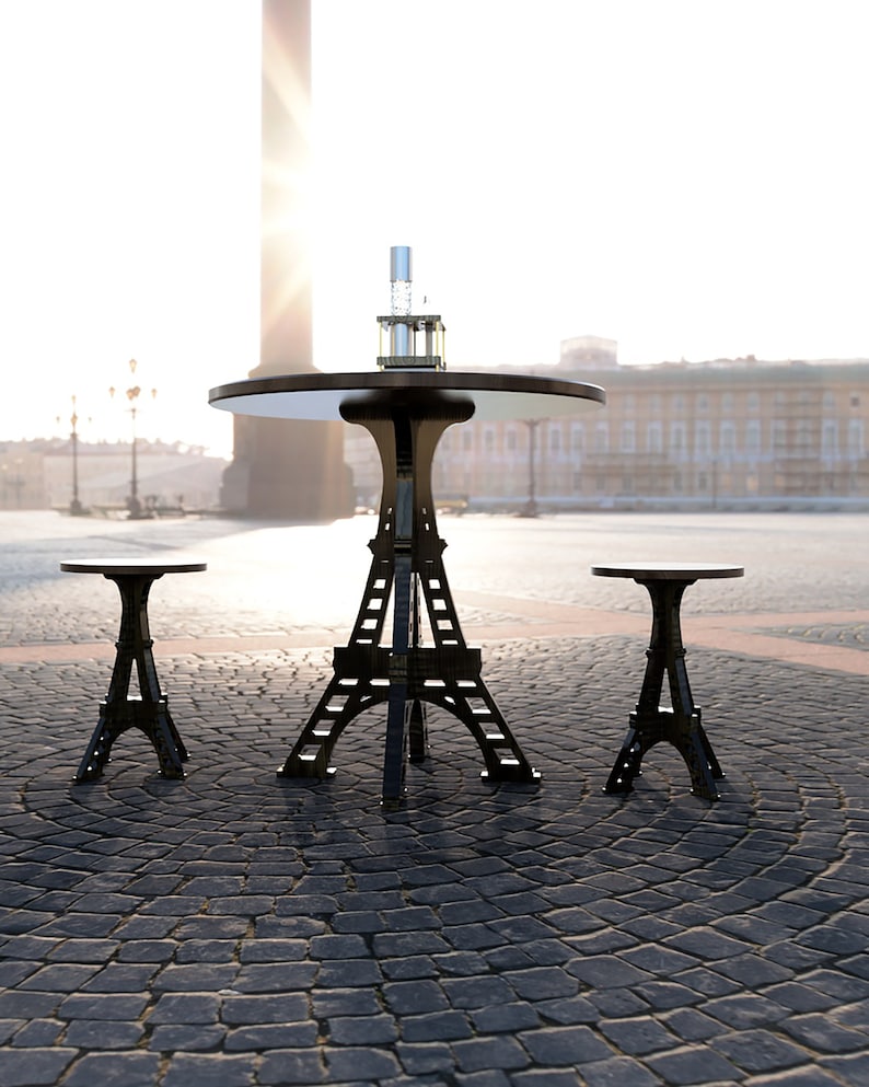 May include: A black metal table and two matching stools shaped like the Eiffel Tower. The table has a round, black tabletop and a clear glass bottle on top.