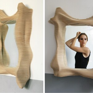 Puede incluir: Un espejo de madera con un marco &uacute;nico, abstracto y ondulado. El marco est&aacute; hecho de finas tiras de madera superpuestas que crean un efecto tridimensional.