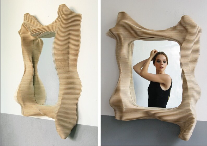 Puede incluir: Un espejo de madera con un marco &uacute;nico, abstracto y ondulado. El marco est&aacute; hecho de finas tiras de madera superpuestas que crean un efecto tridimensional.