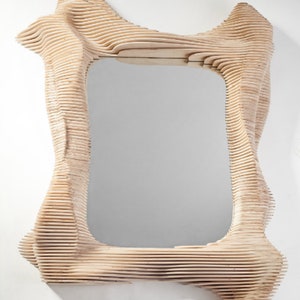 Puede incluir: Un espejo de madera con un marco &uacute;nico, org&aacute;nico y abstracto. El marco est&aacute; hecho de finas piezas de madera superpuestas que crean un dise&ntilde;o fluido y ondulado.