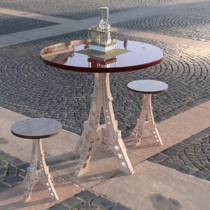 May include: A set of outdoor furniture with a round table and two Eiffel Tower-shaped stools. The table has a red top and a glass surface. The stools are made of wood and have a natural finish.