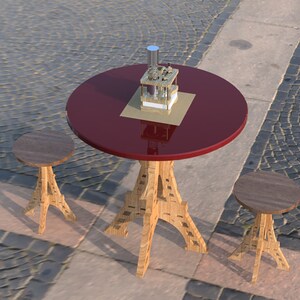 May include: A red round table with a gold metal object on top, and two wooden stools with Eiffel Tower-shaped legs. The table and stools are on a gray cobblestone surface.