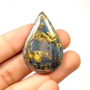 Op de afbeelding: Een traanvormige cabochon van gepolijst pyriet met een draaiende patroon van goud en zwart.