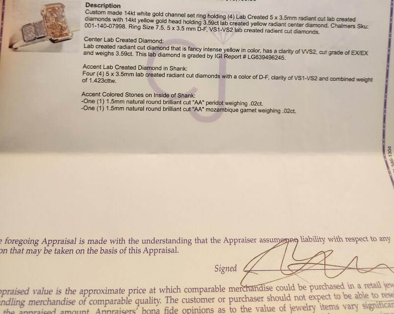 May include: A close-up of an appraisal document for a 14 karat white gold ring with a 3.59 carat lab-created yellow radiant center diamond. The ring also has four 5 x 3.5 mm lab-created radiant cut diamonds in the shank. The appraisal document includes the details of the ring, including the diamond's clarity, cut, and color.