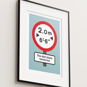 May include: A framed print with a red and white road sign that says "2.0m 6'-6" and a white sign that says "The diet starts tomorrow".