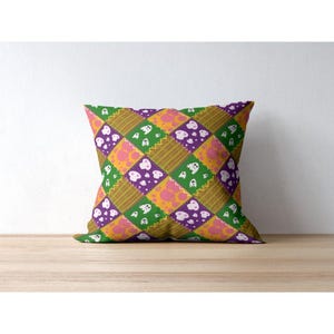 Close-up mockup of a single throw pillow showcasing the repeating patchwork ghost and skull seamless pattern on fabric.
