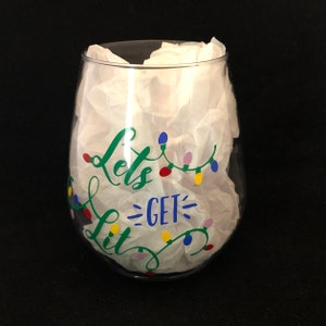 Pode incluir: Uma ta&ccedil;a de vinho de vidro transparente com um desenho de luzes verdes, azuis e amarelas que diz "Let's Get Lit".