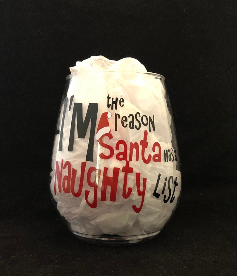 Pode incluir: Uma ta&ccedil;a de vinho de vidro transparente com um design vermelho e preto que diz "Eu sou a raz&atilde;o pela qual o Papai Noel tem uma lista de travessos".
