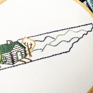 May include: Embroidered design of the state of Tennessee with a cabin, trees, and mountains in shades of green, brown, and blue.