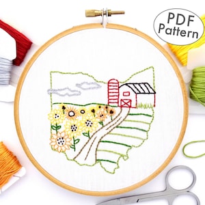 May include: Embroidered pattern of the state of Ohio with a red barn, sunflowers, and a winding road. The pattern is in a wooden embroidery hoop. The image includes the text "PDF Pattern".
