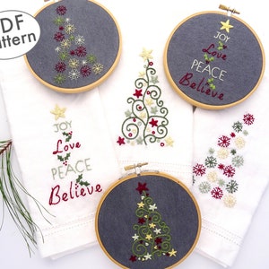 May include: Four embroidery hoop designs featuring Christmas trees with different embroidery patterns. The designs include a traditional Christmas tree with snowflakes, a tree with swirls and stars, a tree with holly and berries, and a tree with the words "Joy, Love, Peace, Believe".