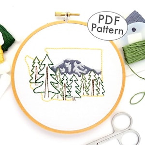 May include: A PDF pattern for an embroidery hoop art project featuring a stylized outline of the state of Washington with a mountain range and trees. The pattern includes floss colors in green, yellow, and gray.