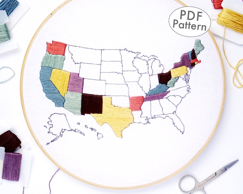 K&ouml;nnte beinhalten: Eine Nahaufnahme eines fertigen Stickprojekts einer Karte der Vereinigten Staaten von Amerika. Die Karte ist auf wei&szlig;em Stoff in einem Reifen gestickt. Die Bundesstaaten sind mit verschiedenen Farben von Stickgarn gef&uuml;llt. Der Text "PDF Pattern" ist in der oberen rechten Ecke des Bildes sichtbar.