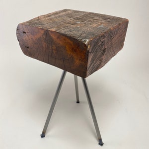 May include: A rustic wooden side table with a natural wood finish and a three-legged metal base.