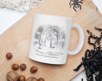 May include: White ceramic mug featuring a cartoon illustration of a person in front of angels, with the text "He wants to know if we have pickleball courts." The mug has a curved handle and is on a wooden surface.