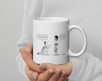 May include: White ceramic mug featuring a cartoon illustration. A man kneels, proposing to a woman, with speech bubbles reading "Will you be my mixed doubles partner?" and "What's your skill level?"