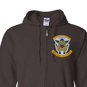 May include: A dark brown zip-up hoodie with a colorful patch featuring a pig with a hat and the text "WHEN PIGS FLY" and "WELL ALL FALL DOWN". The hoodie has a hood, a zipper, and two front pockets.