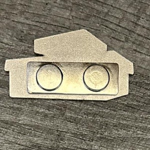 May include: A silver metal name tag shaped like a house with two round magnets on the front.