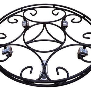 May include: Black metal plant stand with a decorative scroll design and four wheels. The stand is round and has a diameter of approximately 46 cm.