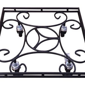 May include: Black metal plant stand with a decorative scroll design and four wheels. The stand is square shaped and has a black metal frame.