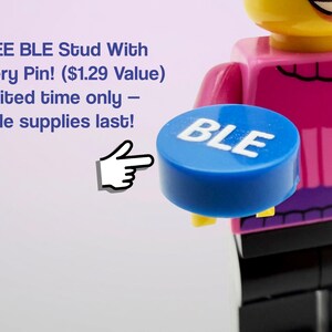 May include: A blue circular stud with the white text BLE printed on the top surface. The stud is held by a yellow plastic figure wearing a pink shirt and black pants. A white hand icon points toward the blue stud, and text reads FREE BLE Stud With Every Pin! ($1.29 Value) Limited time only &ndash; while supplies last!