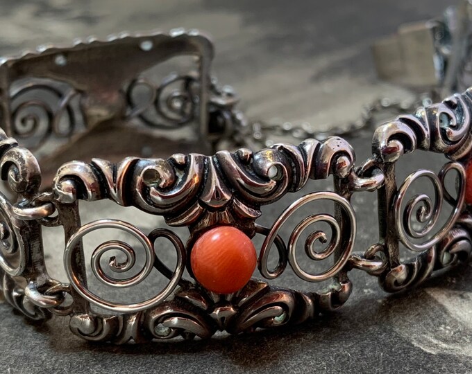 Edwardian silver bracelet. round coral cabochons. Rococo revival decorated panels with scrolls and swirls. 18cm length