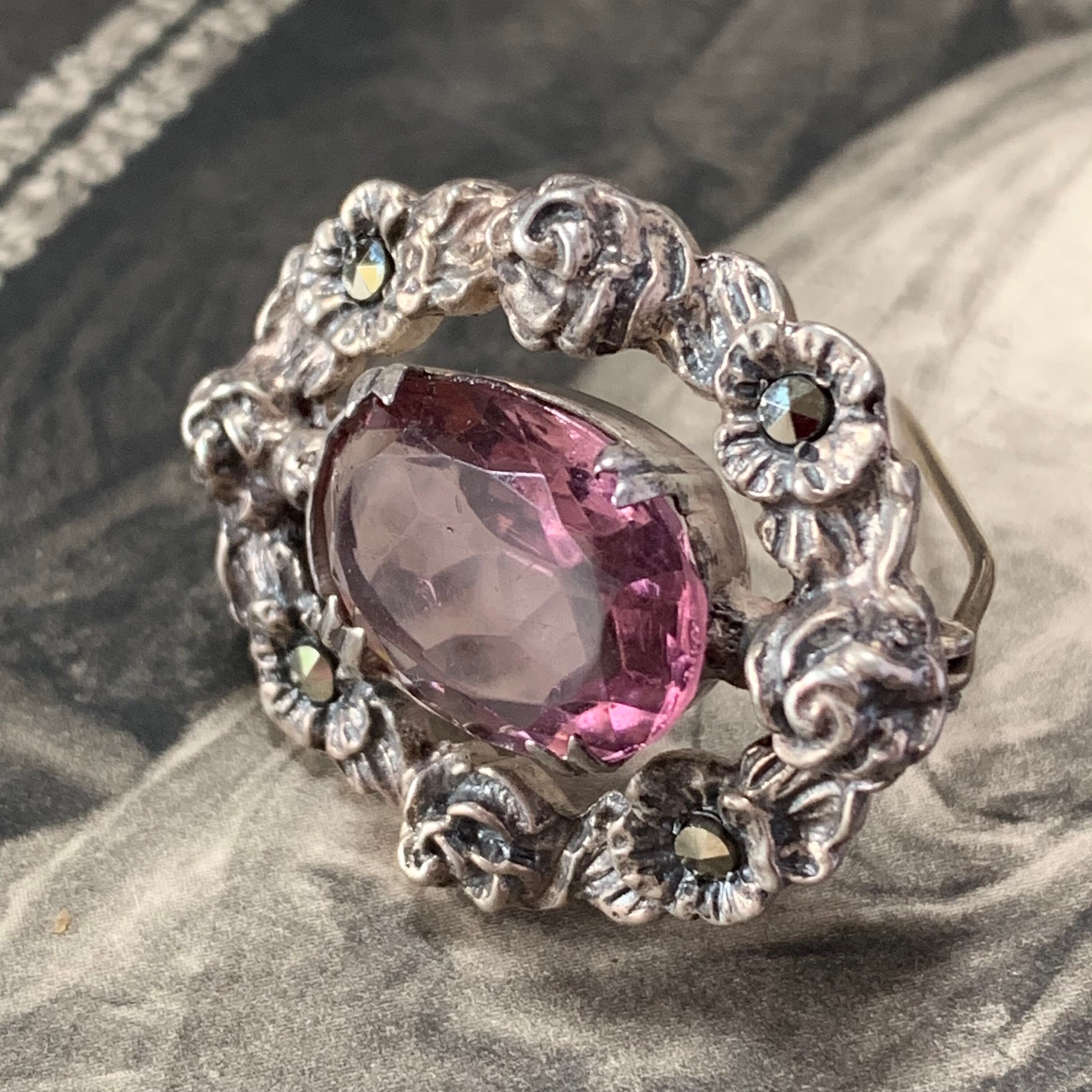 Silver Victorian Brooch Features A Dainty Yet Weighty Design Showcasing Captivating Light Paste Amethyst-Colored Stone At Its Center