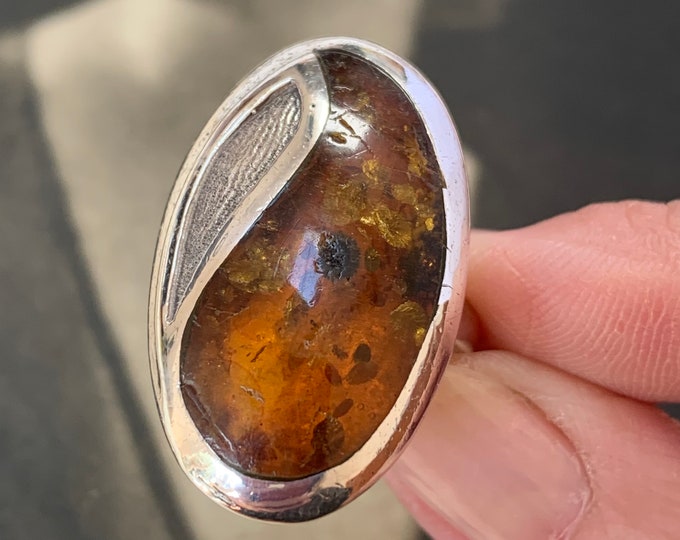 Large, oval cognac-colored amber stone with beautiful organic inclusions. Ring size O 1/2 size 7 1/4  (US). Over 12 grams in weight