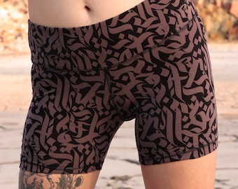 May include: Black and brown patterned athletic shorts. The shorts feature a repeating calligraphic design. The shorts are made of a stretchy material and are designed for athletic activities. The shorts are high-waisted and form-fitting.