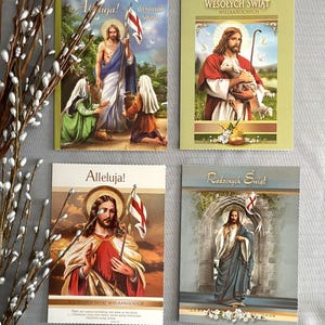 May include: Four Easter greeting cards with religious imagery. The cards feature illustrations of Jesus Christ, with text in Polish. One card shows Jesus holding a lamb, another shows Jesus with a flag, and two others show Jesus with figures.