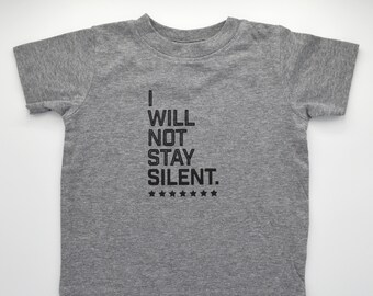 May include: Gray t-shirt with the text "I WILL NOT STAY SILENT." in black lettering and a row of stars below the text.
