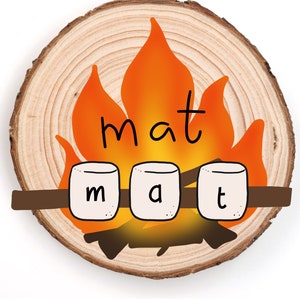 May include: A round wooden slice with a campfire illustration and the word "mat" spelled out with marshmallows on a stick.