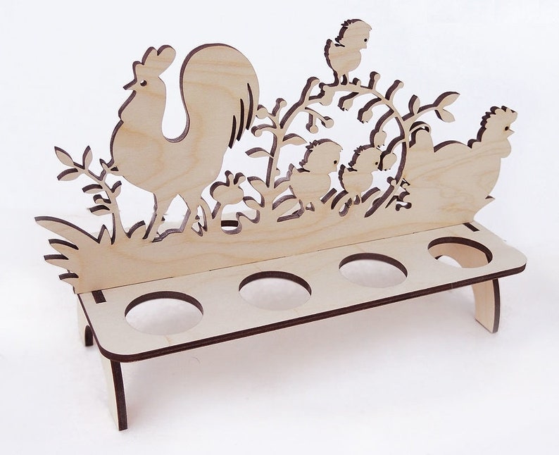 May include: Wooden egg holder with a rooster and chickens design. The holder has six slots for eggs and stands on two legs.